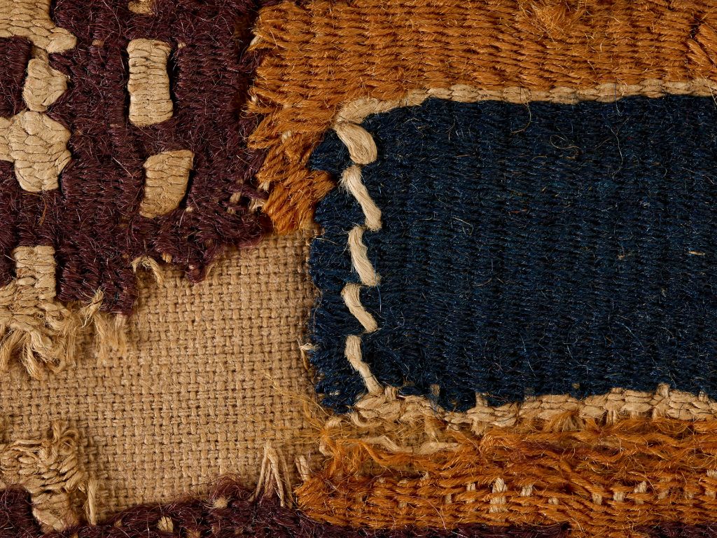 Un morceau de textile tissé aux bords rugueux dans des tons bruns, bleus et beiges