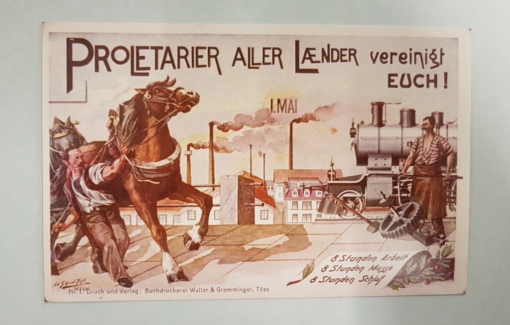 Auf dieser Postkarte sbefinden sich zwei Arbeiter, einer mit Pferd, der andere mit Lokomotive und Handwerksmaterial. Oben findet sich der Aufruf, die Proletarier aller Länder sollen sich vereinigen.