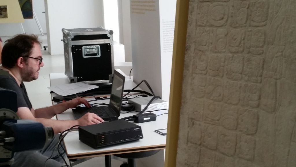 Das Foto zeigt Christian Prager am Laptop neben der Relieftafel.