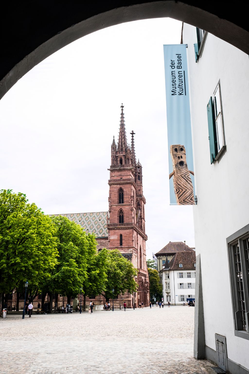 Das Bild zeigt das Eingangstor des Museums. Durch das Tor hindurch sieht man den Münsterplatz und im Hintergrund das Basler Münster