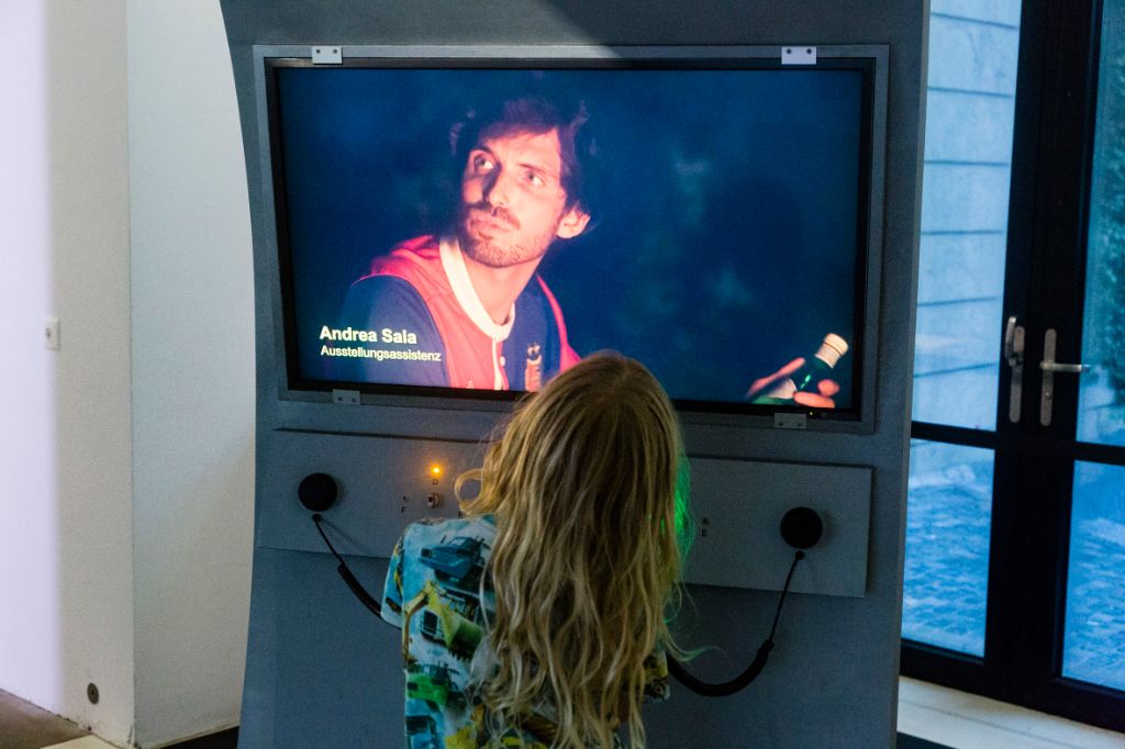 Ein Kind steht vor einem Bildschirm in der Ausstellung «Sonne, Mond und Sterne». Es ist ganz vertieft. Auf dem Bildschirm ist ein Fussballer zu sehen.