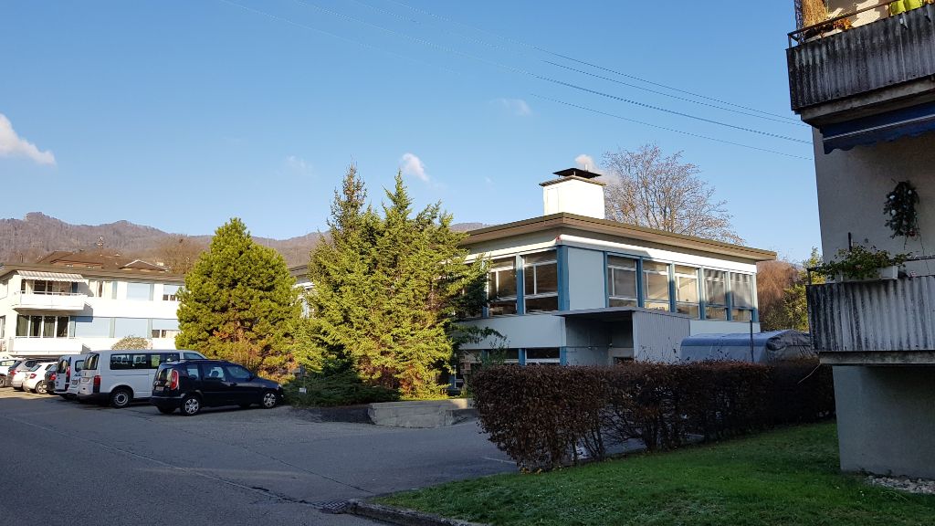 Der Himmel auf dem Bild ist blau, trotz winterlicher Temperaturen von um die 0 Grad. Das Haus darunter hat ein flaches Dach und grosse Fenster.