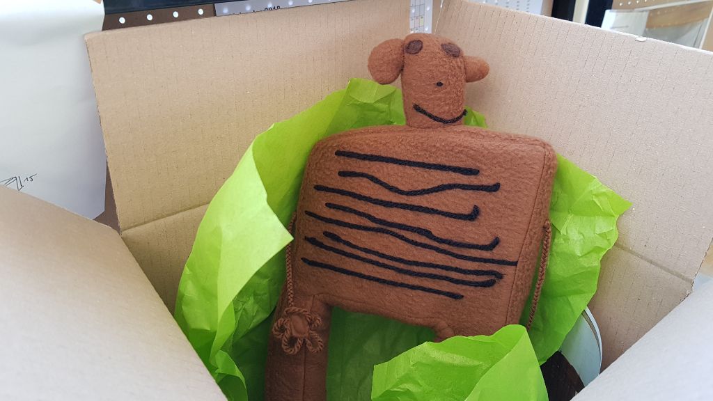 Ein brauner Bär, der ein wenig aussieht wie ein Laib Brot, sitzt im Paket und ist bereit für die Überfahrt ins neue Zuhause.