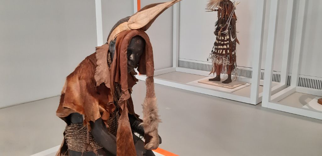 Das Foto zeigt die Ausstellungsfigur eines «Herero-Typus» aus Hamburg. Die Figur trägt viele Gegenstände der Herero, die einst gesammelt wurden: z.B. ein Gürtel, eine Kappe, ein Mantel, Hals- und Beinbänder, Beinringe sowie Armspangen. 