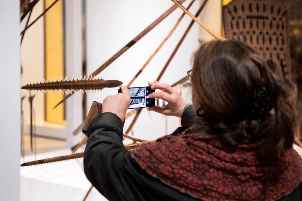 Eine Frau fotografiert in der Ausstellung einen Dolch.