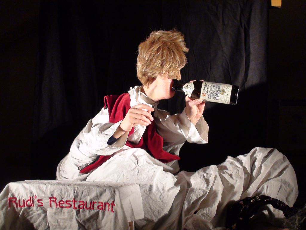 Das Foto zeigt Füsse und Hände als Kellner, der selber grad aus einer Flasche Wein trinkt