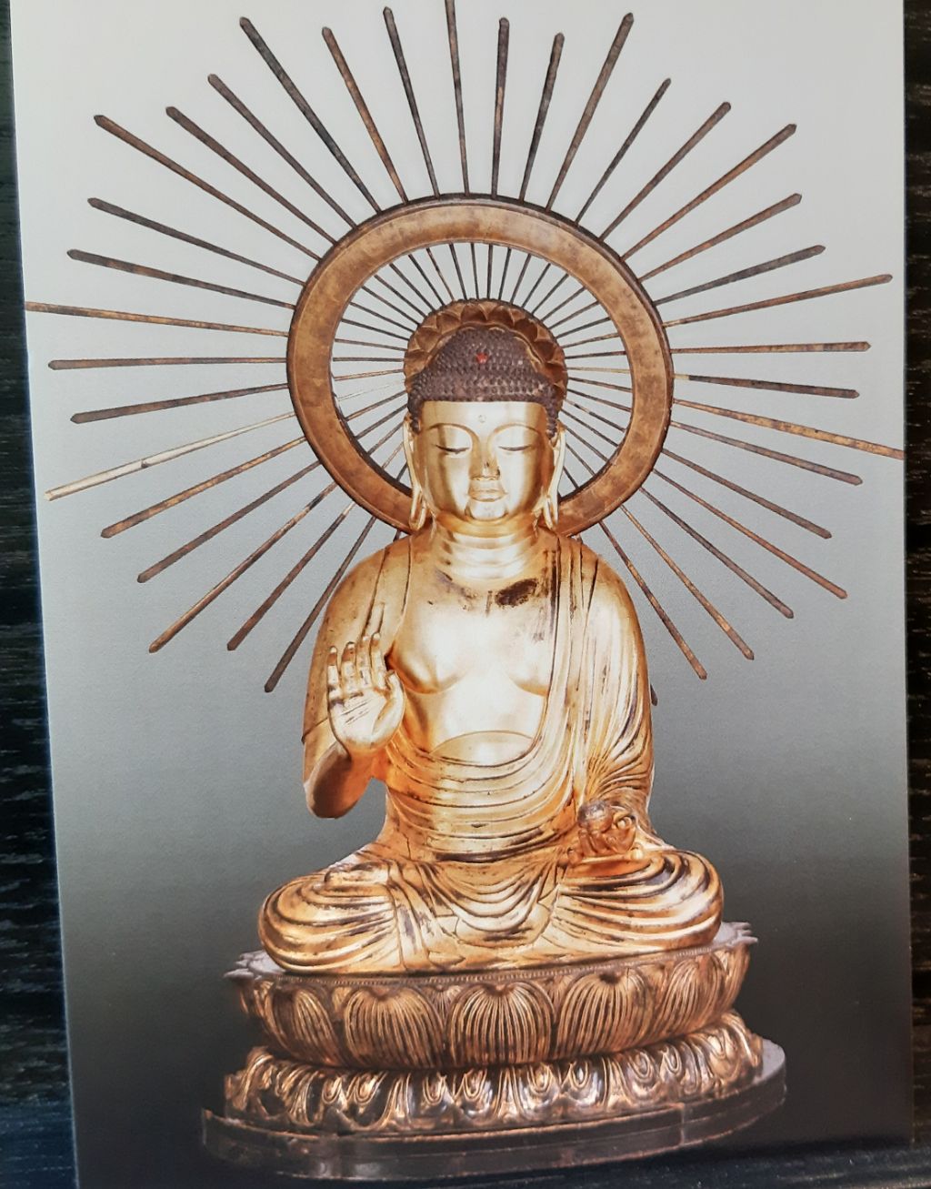 Die Kart zeigt eine Buddha-Statuette. Der Buddha ist ganz golden und trägt eine grosse Gloriole.