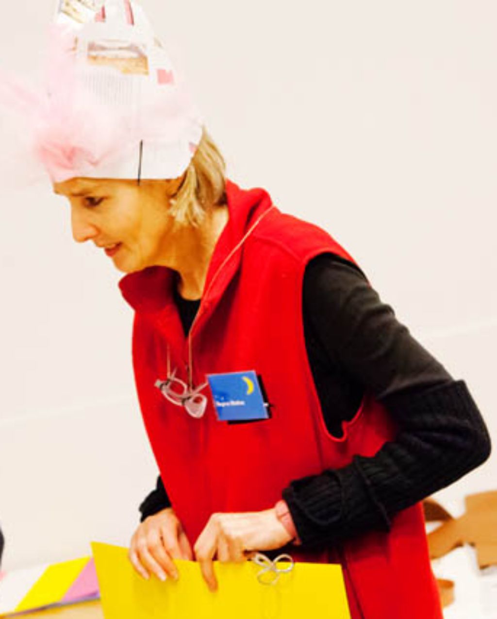 Das Foto zeigt Regina Mathez in Aktion im Workshop «Hut ab». Sie selber trägt einen Papierhut mit Museumsschriftzug und Logo