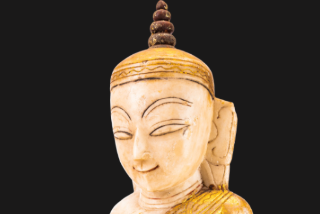 Gesicht einer Figurine von Buddha mit geschlossenen Augen, lächelndem Mund und langem linken Ohrläppchen