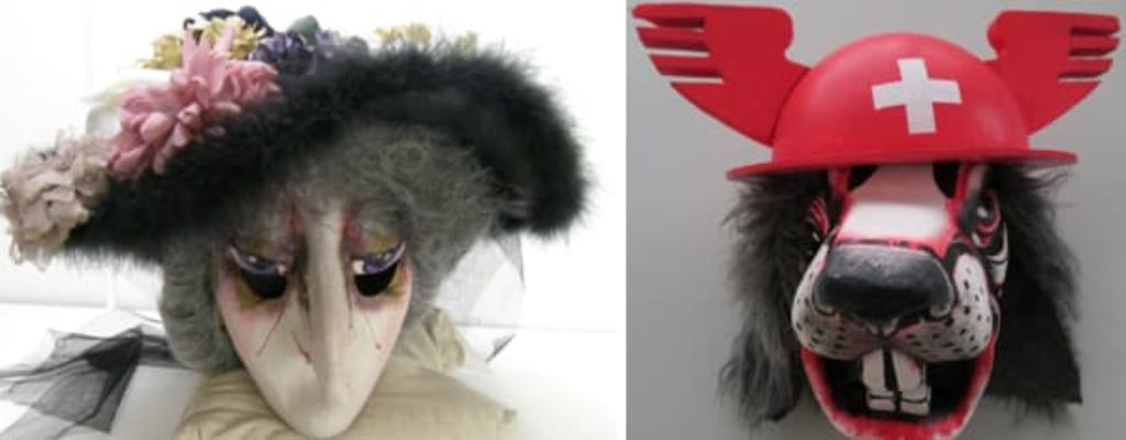 Zwei Masken: links ein Frauengesicht mit spitzer Nase, grauem Wuschelhaar und einem Hut mit Blumen besteckt; rechts ein Tierkopf mit einem roten Messe-Schweiz-Hut