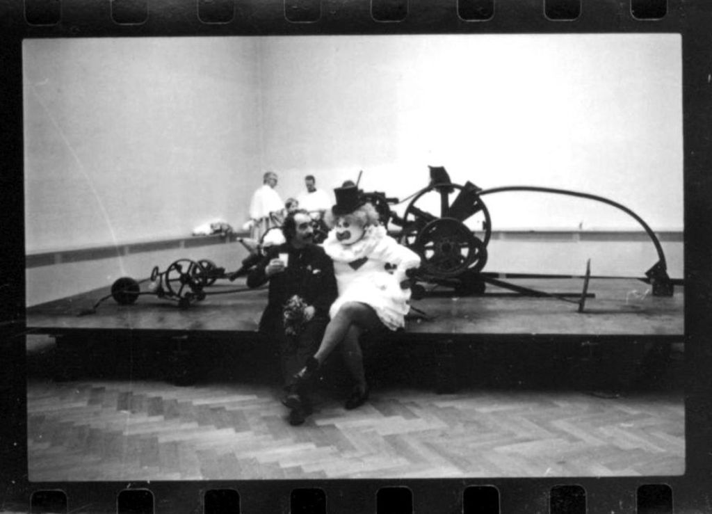 Sitzender Jean Tinguely mit einem Clown vor einem Kunstwerk von ihm