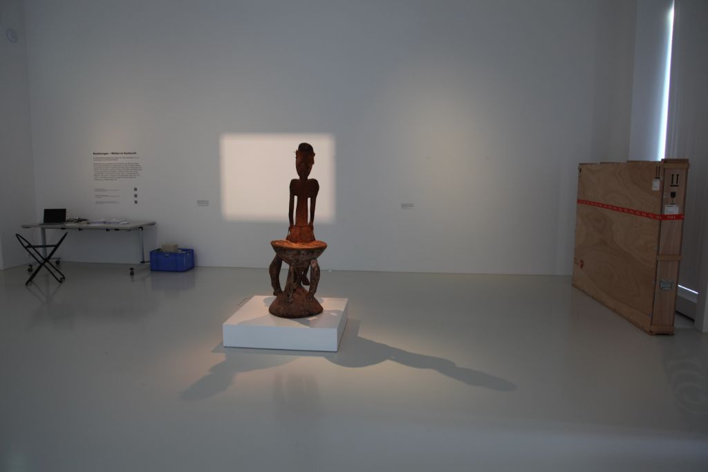 Holzfigur von hinten, allein im Ausstellungsraum