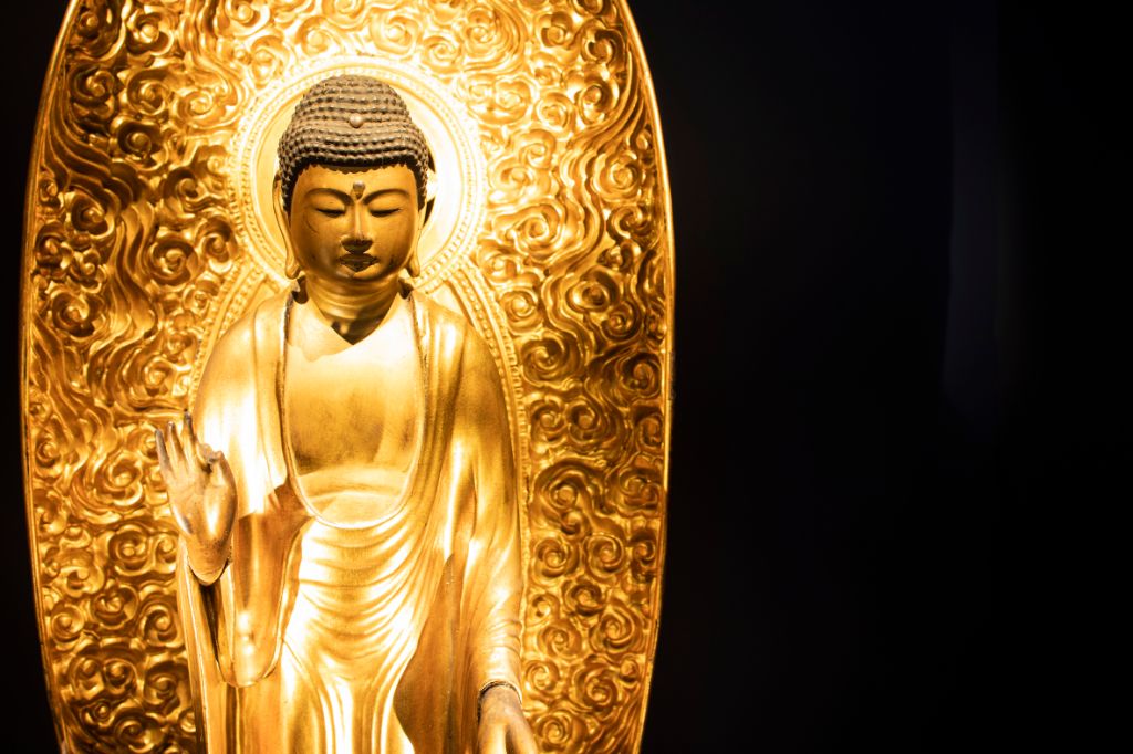 goldene, grosse Buddhafigur, die mit rechter Hand Zeigefinger und Daumen zusammendrückt