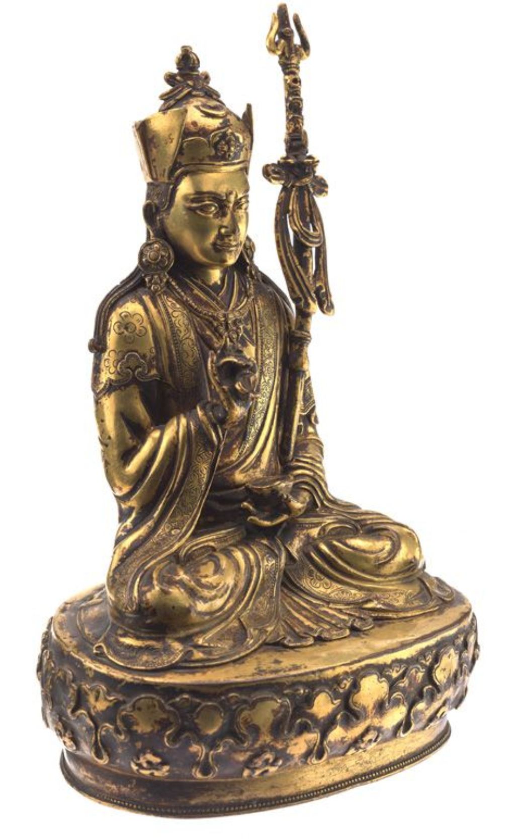 Goldene Buddhafigur, der Buddha trägt eine Kopfbedeckung und hält in den Händen Ritualgegenstände. Er sitzt auf einem Podest.