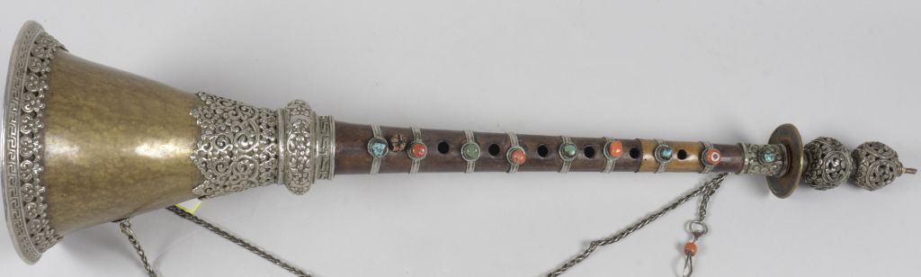 Instrument mit zwei silbernen Kugeln am Mundstück, sechs Löchern, Perlenverzierungen in Blau und Orange, unten weitet sich das Instrument.