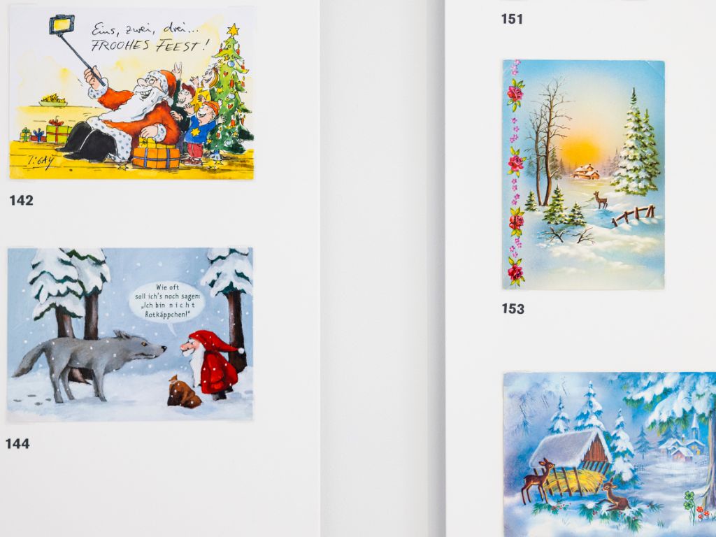 Vier Karten auf weisser Wand: Links oben eine Karte mit einem Weihnachtsmann und Kindern, links unten ein Weihnachtsmann mit Wolf, rechts oben eine Winterlandschaft mit Reh und rechts unten ebenfalls eine Szene im verschneiten Wald mit zwei Rehen bei einer Futterkrippe.