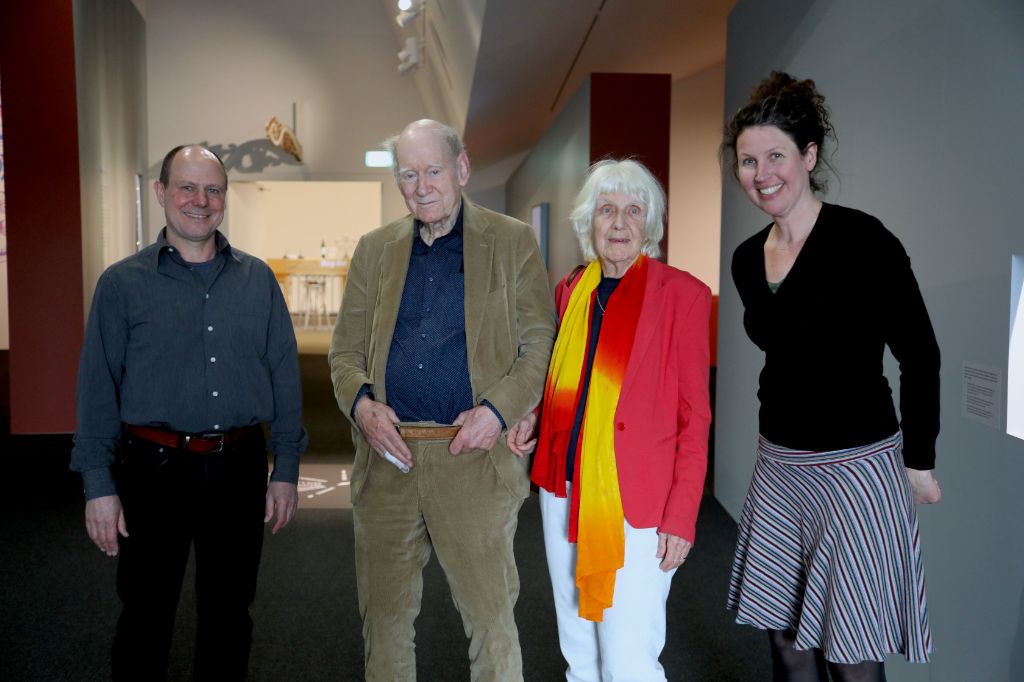 Vier Personen stehen lächelnd in einem Innenraum vor einer Ausstellung