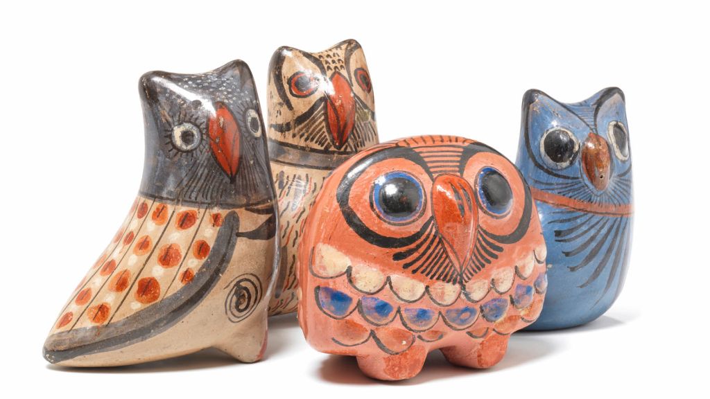 Des hiboux en céramique colorés en beige, orange et bleu, ensemble sur fond blanc.
