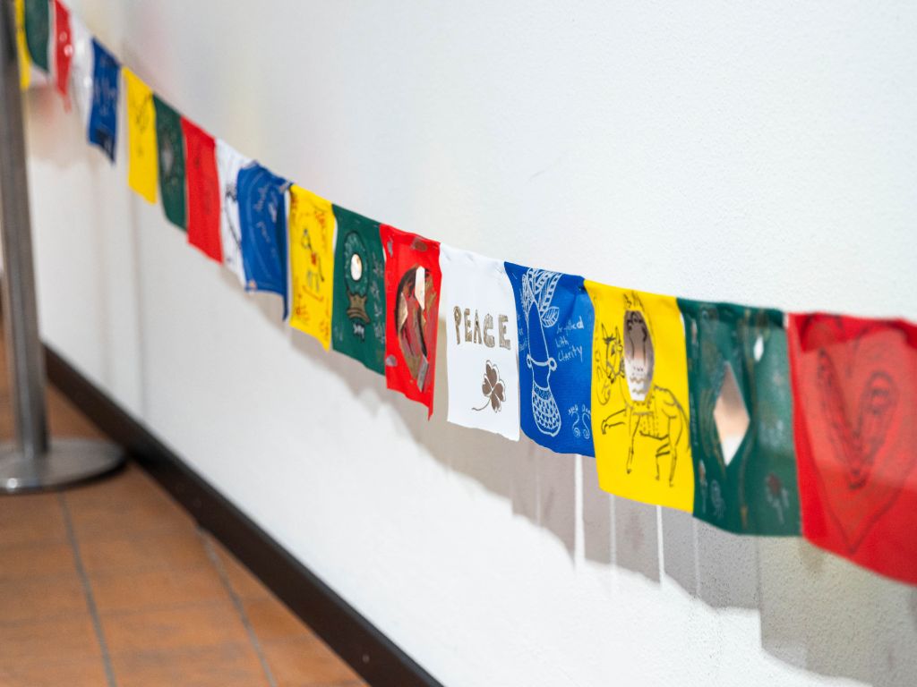 Aufgehängte buddhistische Fahnen vor weisser Wand