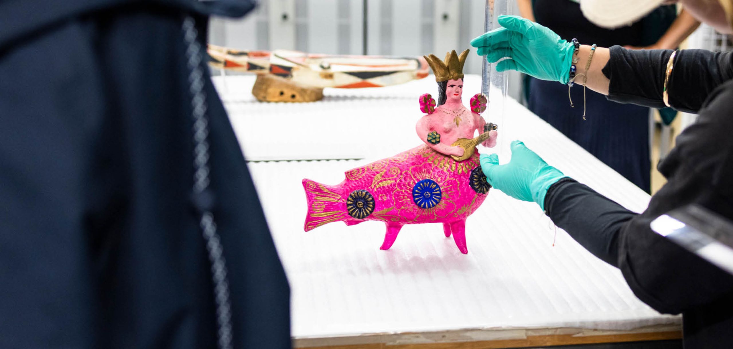 Eine bunte, pinke Skulptur mit Fischkörper und menschlichem Oberkörper wird vermessen