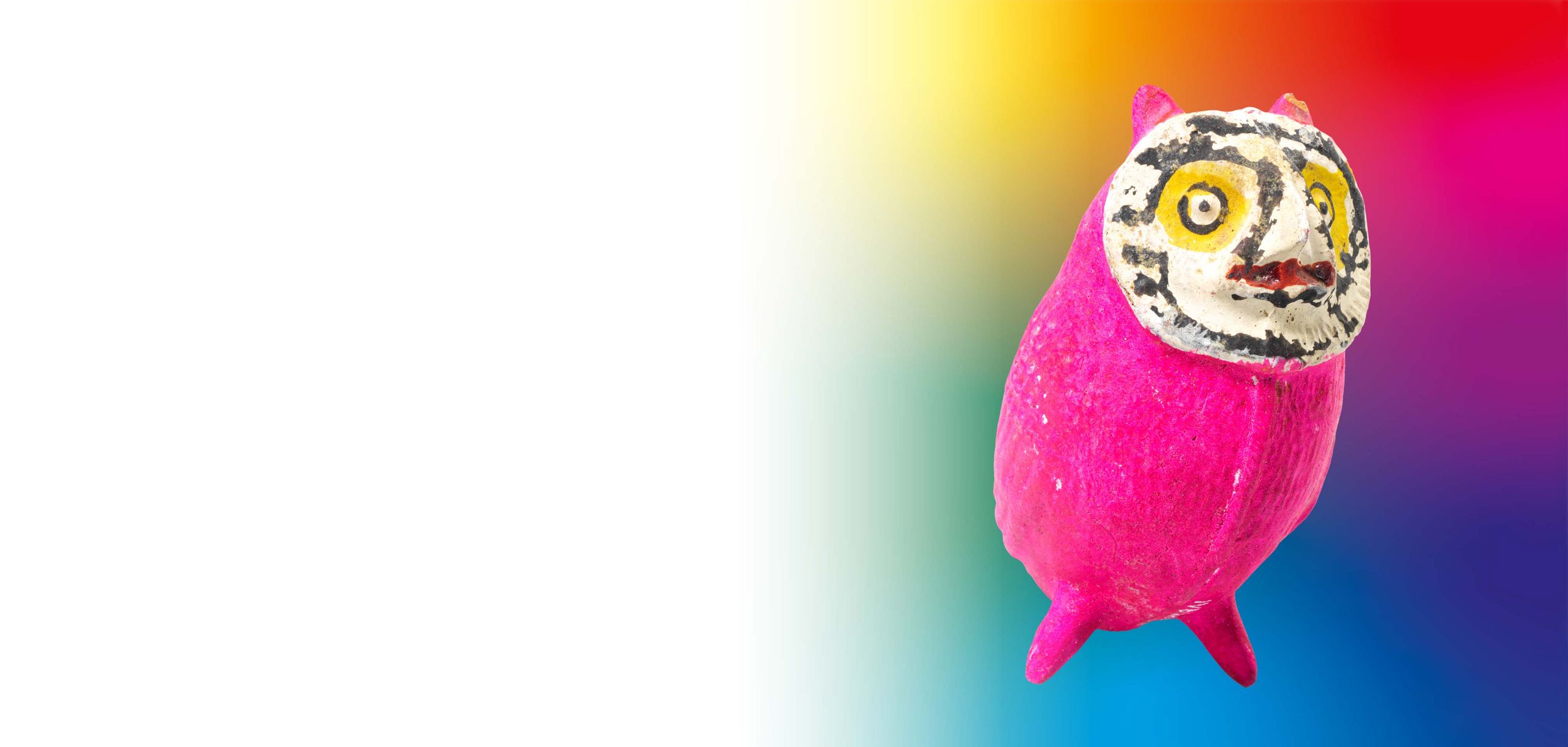 Eine pinke Eule mit grossen Augen steht vor einem bunten, verschwommenen Hintergrund
